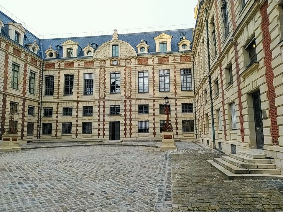 Courtyard surrounded with red-brick buildings faced in stone. A clock is visible on the opposite wall