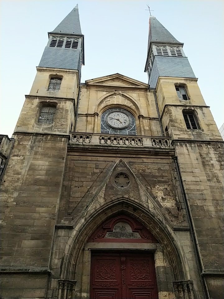 Two small church steeples. Between them is a clock showing 4:48. Below all of this is an archway with a red double door
