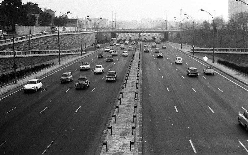 Black and white photograph of 8-lane highway, with busy but moving traffic