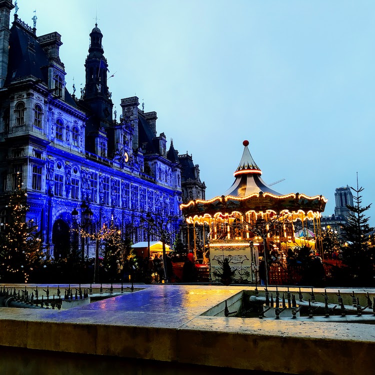 Paris Hôtel de Ville with a Christmas village on the square in front, including trees and a carousel