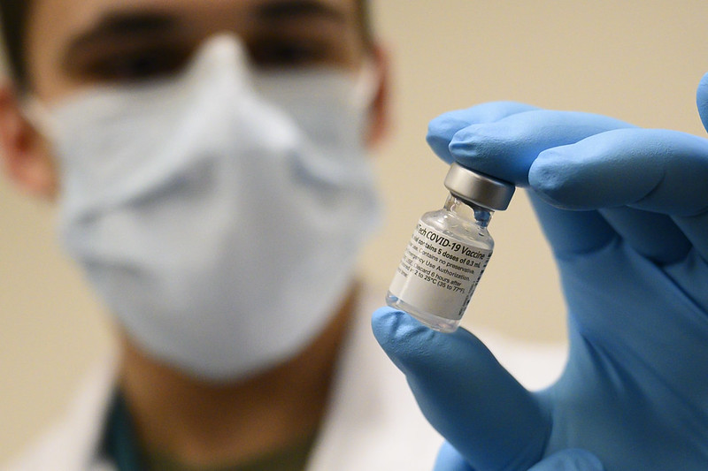 Man holding vial labelled “Pfizer/BioNTech COVID-19 Vaccine”