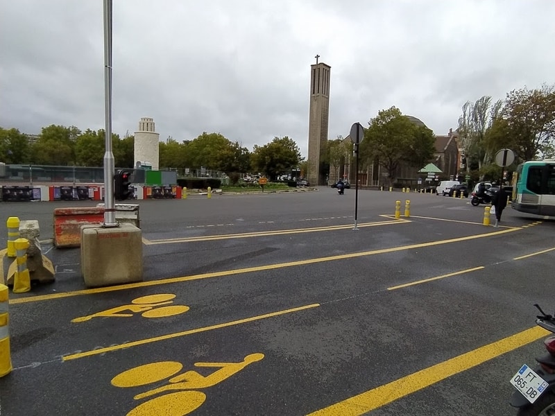 Large roundabout with yellow-painted cycle lanes demarcated by concrete blocks and yellow plastic wands