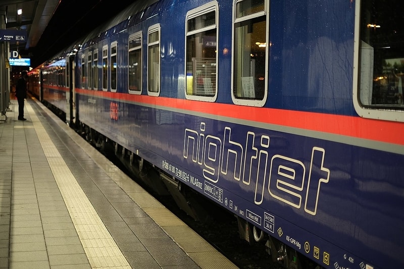 Nightjet train standing on a platform under a dark sky