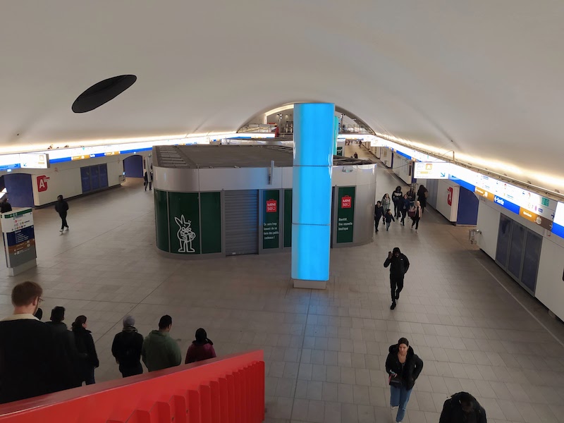 Station concourse with vaulted ceiling over a large open space. Mini buildings in the centre bear signs promising new shops soon