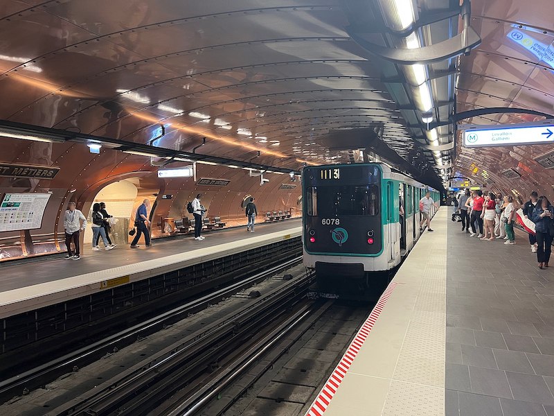 Old metro train, painted turquoise and white, in copper-clad station