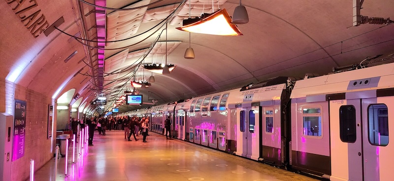 Colourfully-lit underground train platform with new train standing at it