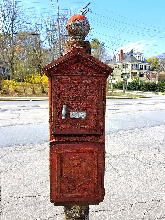 Red metal box in street with door with white handle