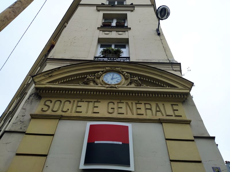 Building façade. Above the ground floor doorway is a large Société Générale logo, with the name of the bank engraved above it. Above that is a clock set in ornate stonework