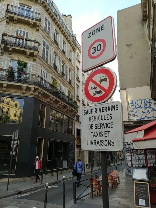 Signs at the entrance to a narrow street: “Zone 30” and “no motor vehicles” pictographic sign. The latter “sauf riverains, véhicules de service, taxis et livraisons”
