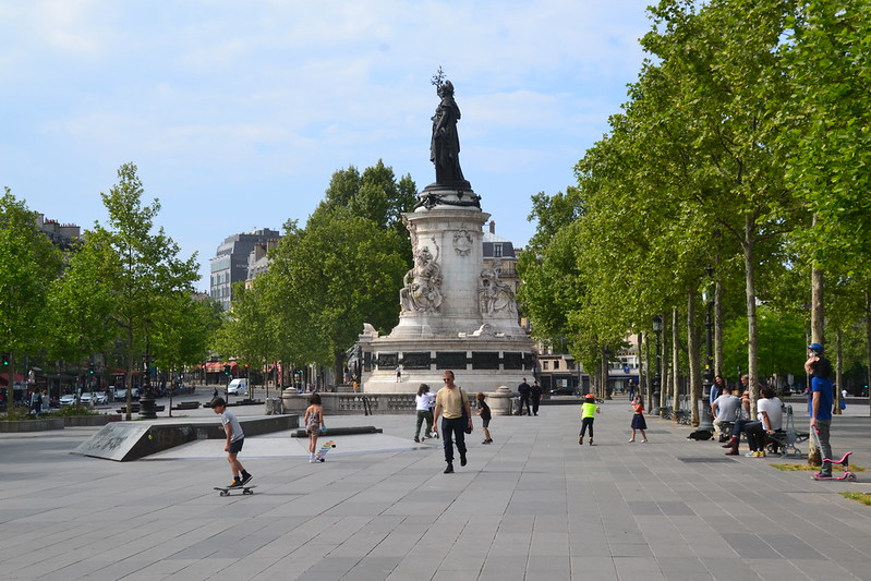 Children with skateboards and scooters in front of the statue of Marianne in the Place de la République