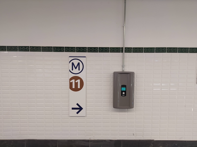 White tiles with a green trim. A large sign points the way to M11.