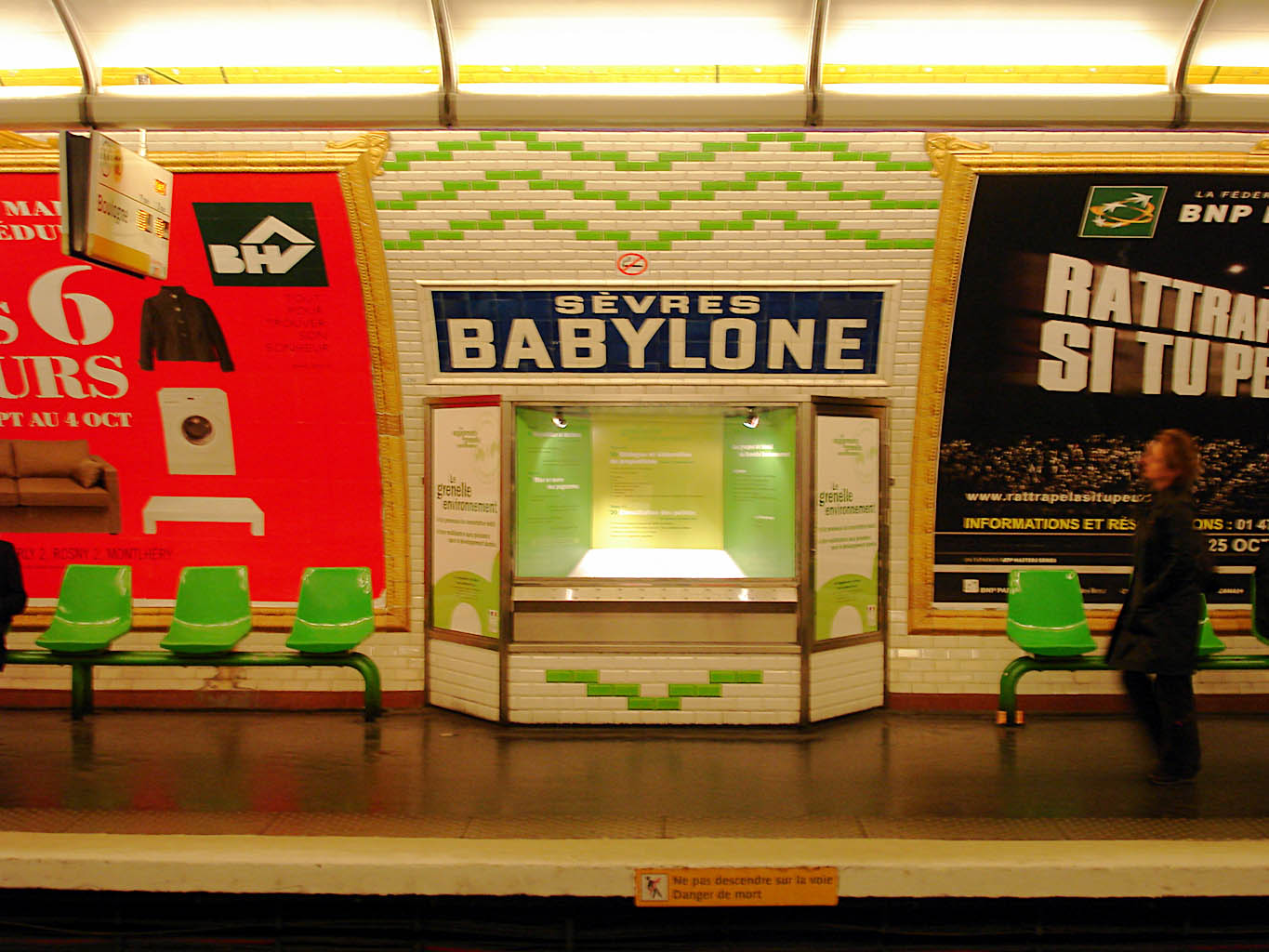 Metro station platform. A sign reads SÈVRES BABYLONE, with the word SÈVRES in small letters and BABYLONE in large