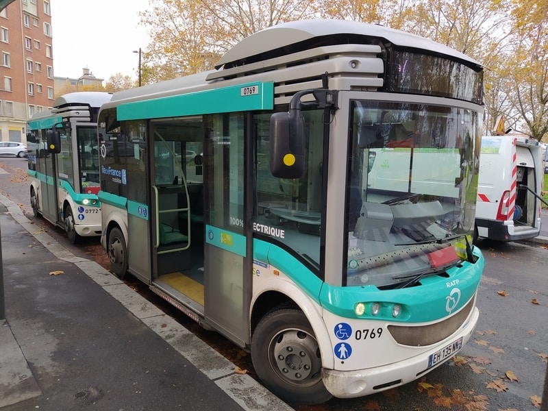 One minibus waiting behind another. The front bus's doors are open