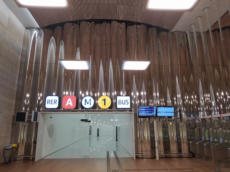 A passageway with large signs above, reading RER A / M1 / BUS