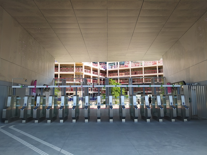 A row of 14 automated ticket gates, looking outward with a construction site in the background