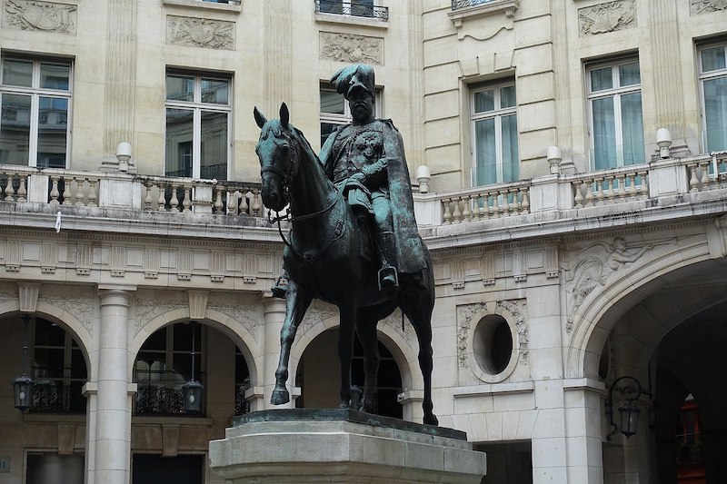 Statue of a man seated on a horse, surrounded by grand buildings