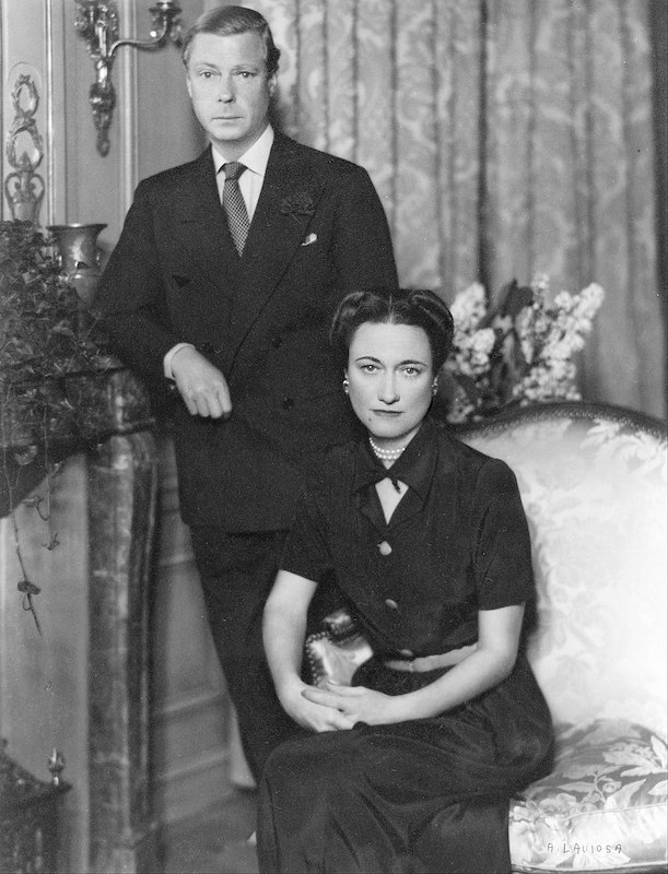 Black and white photograph of a seated lady and a standing gentleman, looking seriously at camera