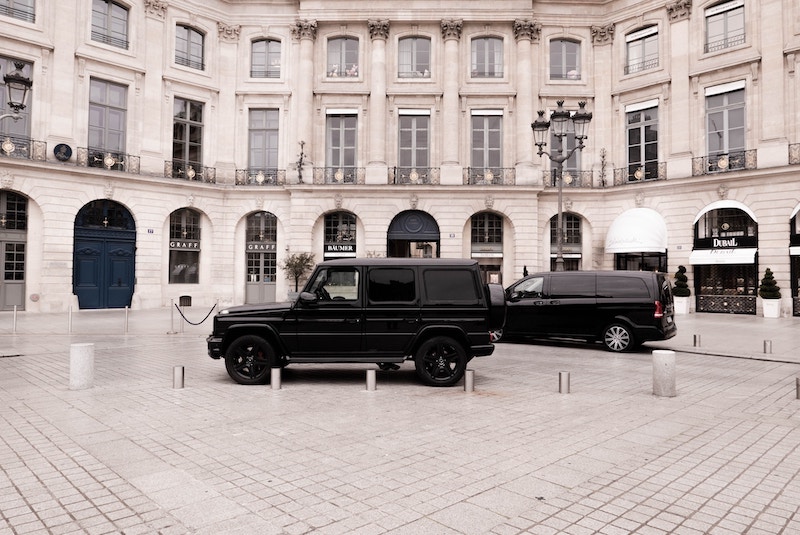 A black truck parked on a stone plaza in front of a large building