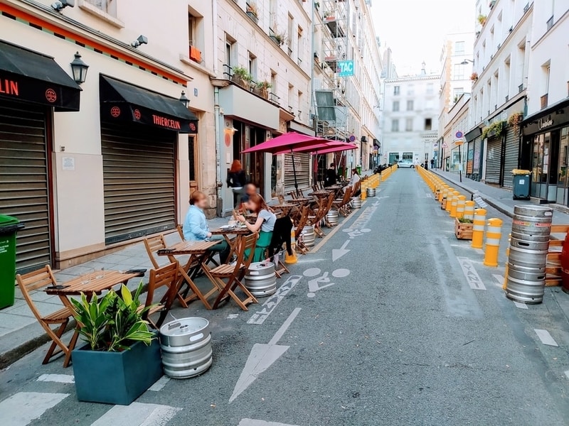 Paris street with parking blocked off for restaurant tables and pedestrian space