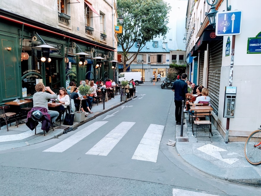 Paris street with restaurant tables occupying both pavements