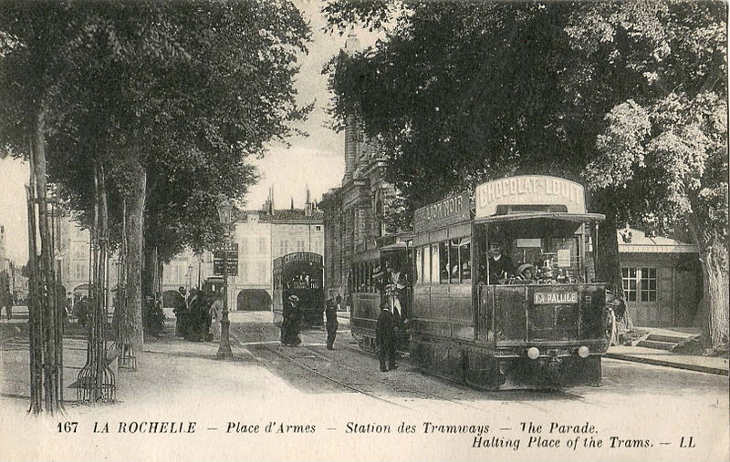 A single-car tram follows a two-car vehicle at a station. Postcard labelled 167 LA ROCHELLE – Place d'Armes – Station des Tramways – The Parade. Halting Place of the Trams. – LL