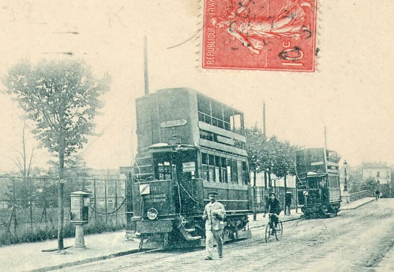 Double-decker tramways parked and plugged in to electricity terminals at the side of the road
