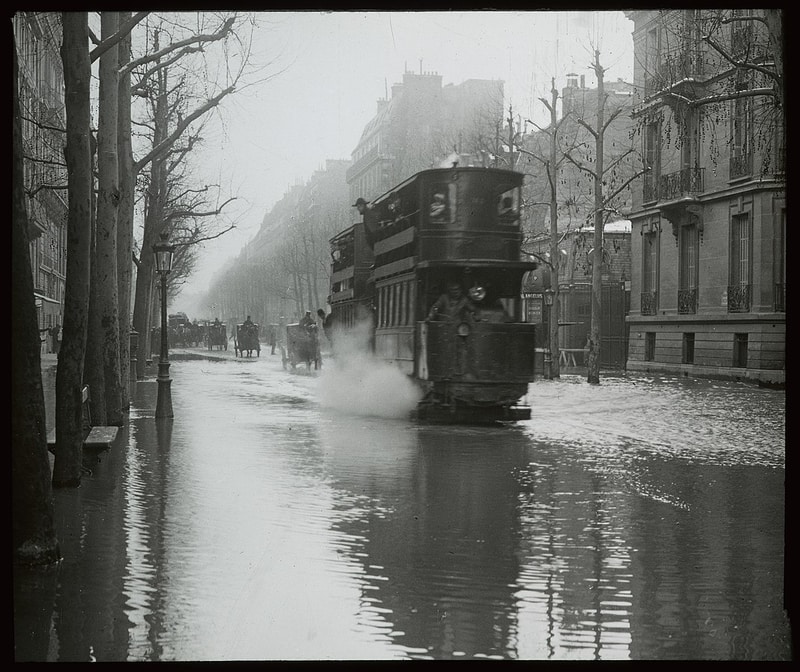Steam double-decker tram running through shallow water