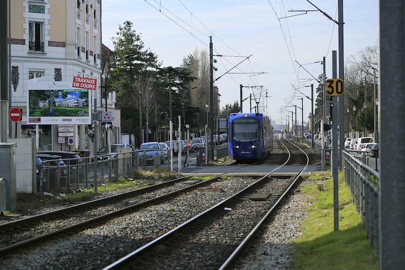 Dark blue tram-train vehicle at a crossroads